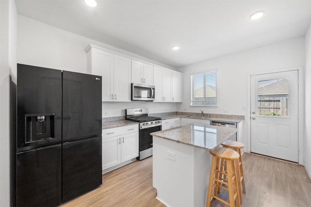 kitchen with a sink, stainless steel appliances, a center island, and white cabinetry