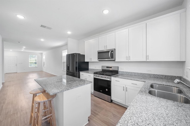 kitchen featuring visible vents, a sink, open floor plan, a center island, and stainless steel appliances