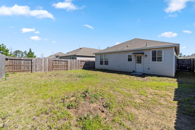 rear view of house featuring a yard and a fenced backyard