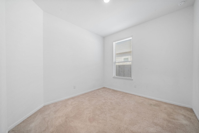 spare room with light colored carpet and baseboards