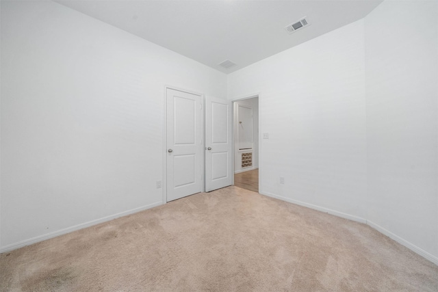 unfurnished room with visible vents, baseboards, and light colored carpet