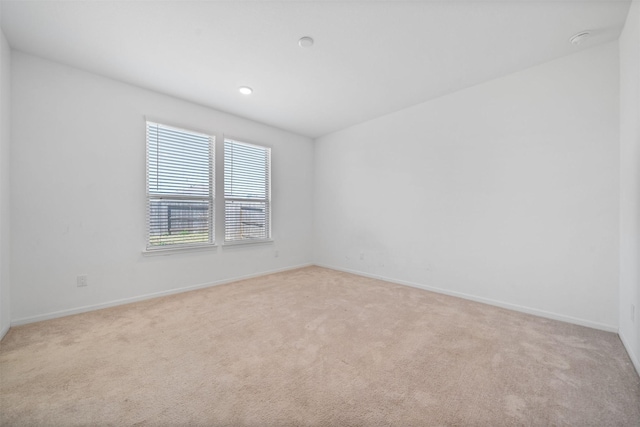 unfurnished room with baseboards and light colored carpet