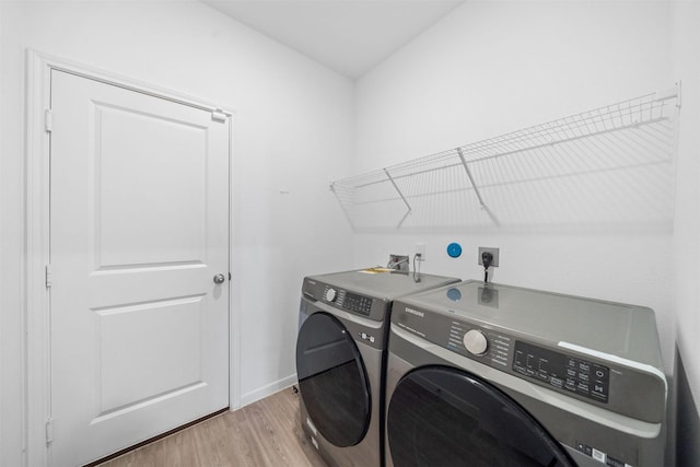 washroom featuring light wood-style flooring, baseboards, washing machine and dryer, and laundry area