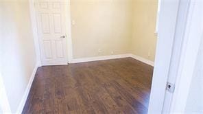 spare room featuring dark wood finished floors and baseboards