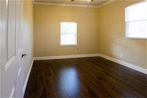 empty room featuring ceiling fan, baseboards, ornamental molding, and dark wood-style flooring