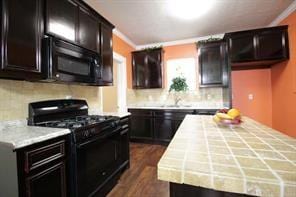 kitchen with dark wood finished floors, crown molding, gas stove, and tasteful backsplash