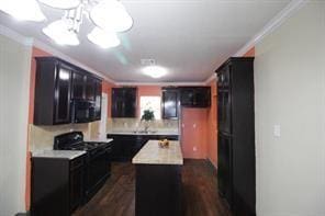 kitchen with black gas range, a kitchen island, crown molding, and light countertops