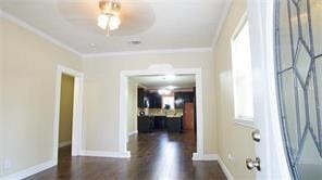 foyer with crown molding, baseboards, and wood finished floors