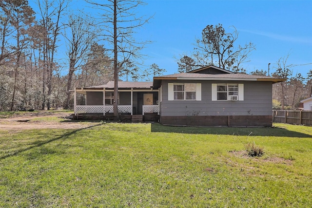 view of front of house featuring cooling unit, fence, a front lawn, and a sunroom