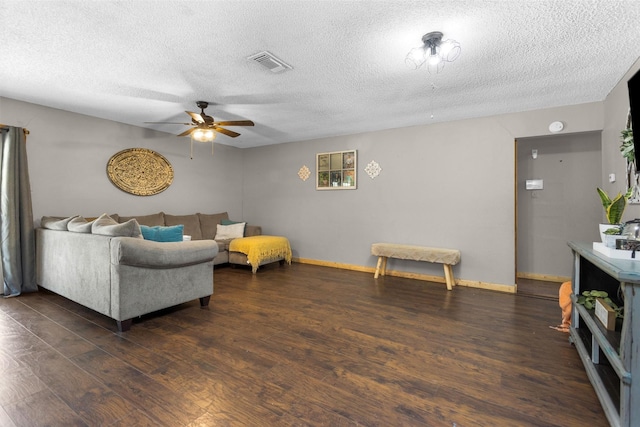 living room featuring visible vents, dark wood-type flooring, baseboards, ceiling fan, and a textured ceiling