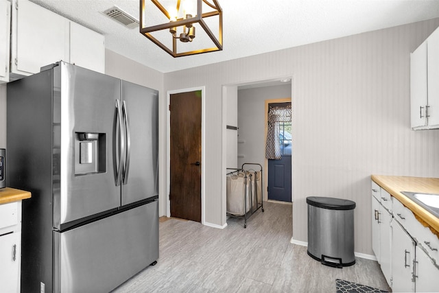 kitchen with visible vents, white cabinets, stainless steel fridge with ice dispenser, and light wood-style flooring