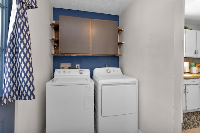 laundry area featuring cabinet space, a textured ceiling, and washing machine and dryer