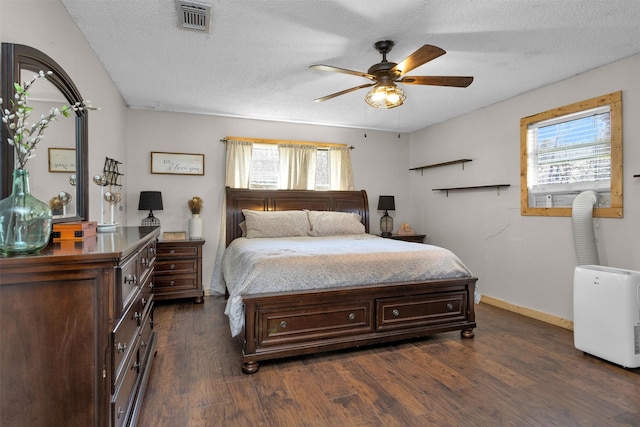 bedroom featuring a ceiling fan, baseboards, visible vents, dark wood-style flooring, and a textured ceiling