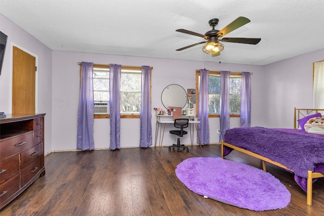 bedroom featuring multiple windows, a textured ceiling, and dark wood-style flooring