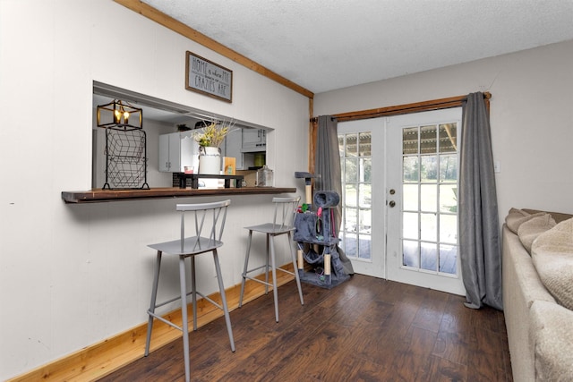 interior space with french doors, a textured ceiling, a kitchen bar, and hardwood / wood-style floors