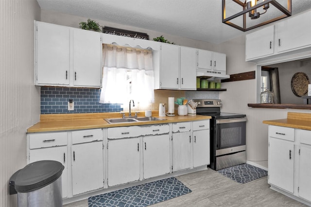 kitchen with stainless steel electric stove, a sink, light countertops, white cabinets, and under cabinet range hood