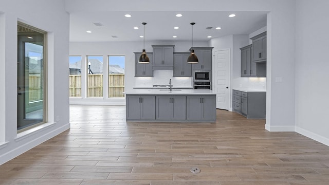 12247 Sweet Gum Dr, Mont Belvieu, TX 77523 - kitchen featuring gray cabinetry, stainless steel oven, black microwave, light countertops, and light wood-style floors