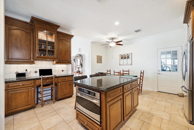 kitchen featuring light tile patterned floors, tasteful backsplash, appliances with stainless steel finishes, and ceiling fan