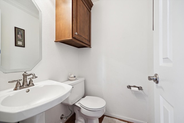 bathroom featuring a sink, baseboards, and toilet