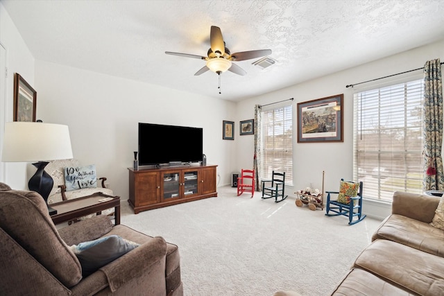 living area with visible vents, light colored carpet, a ceiling fan, and a textured ceiling