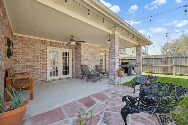 view of patio featuring ceiling fan, fence, french doors, and grilling area