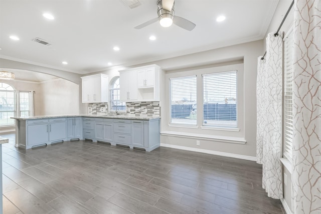 kitchen featuring tasteful backsplash, visible vents, a peninsula, and a sink