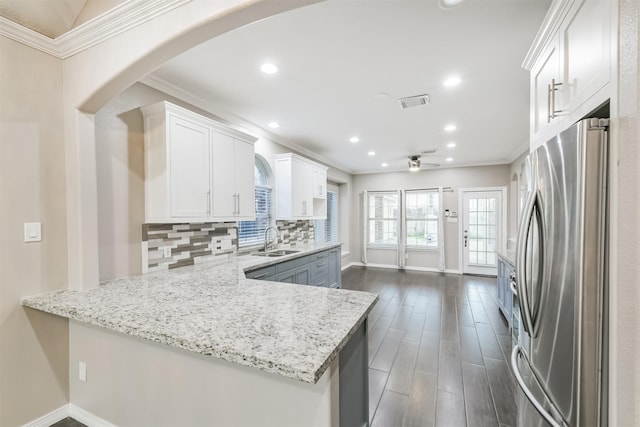 kitchen with freestanding refrigerator, ornamental molding, a sink, white cabinets, and backsplash