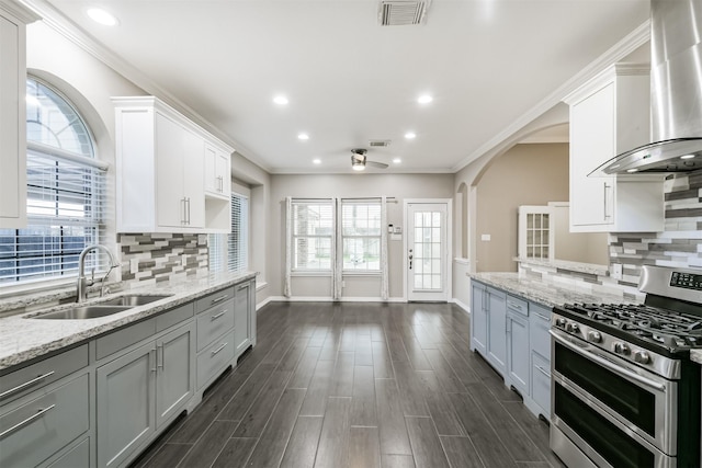 kitchen featuring visible vents, dark wood-type flooring, range with two ovens, wall chimney exhaust hood, and a sink