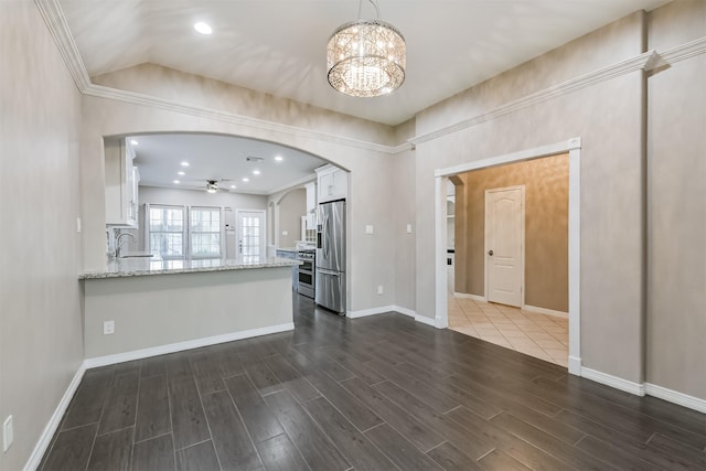 kitchen featuring dark wood-type flooring, light stone counters, arched walkways, white cabinets, and stainless steel appliances