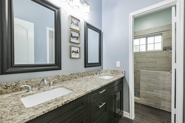 bathroom featuring double vanity, a walk in shower, and a sink