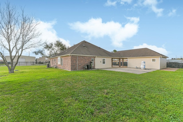 rear view of house with fence, a patio area, brick siding, and a lawn