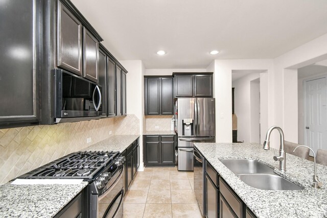 kitchen featuring a sink, light stone counters, appliances with stainless steel finishes, and light tile patterned floors