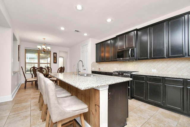 kitchen featuring light stone counters, visible vents, a sink, appliances with stainless steel finishes, and tasteful backsplash