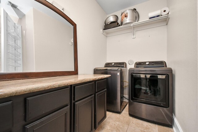 washroom with light tile patterned floors, baseboards, separate washer and dryer, and cabinet space