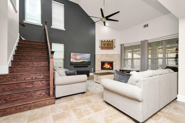 living area featuring visible vents, high vaulted ceiling, ceiling fan, and stairs