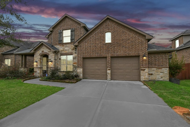 traditional home featuring stone siding, brick siding, an attached garage, and driveway