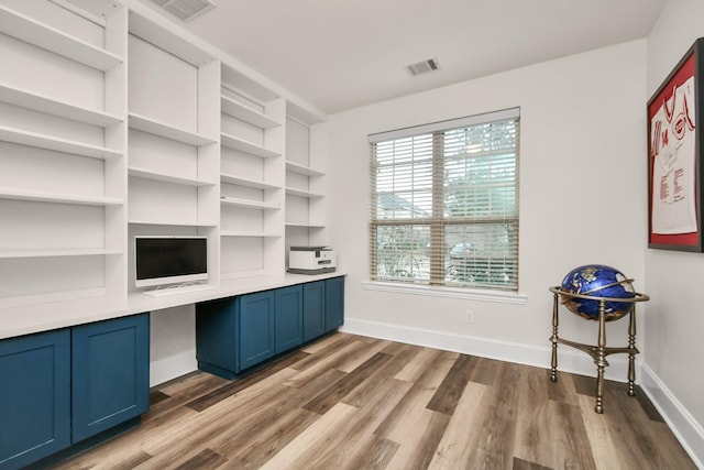 home office with wood finished floors, baseboards, visible vents, and built in study area