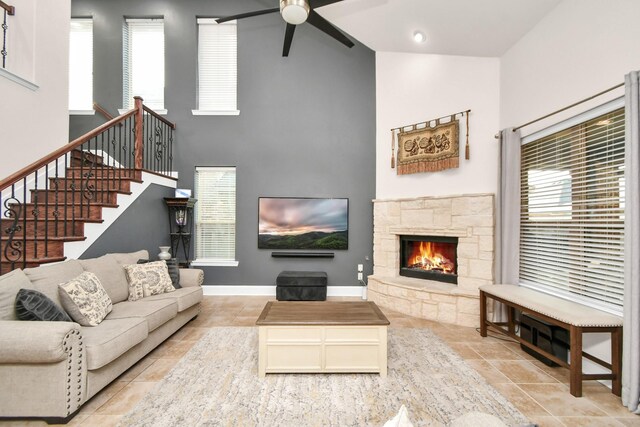 living area with a healthy amount of sunlight, a fireplace, stairs, and a ceiling fan