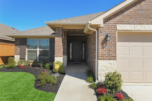 entrance to property featuring a garage, stone siding, brick siding, and a shingled roof