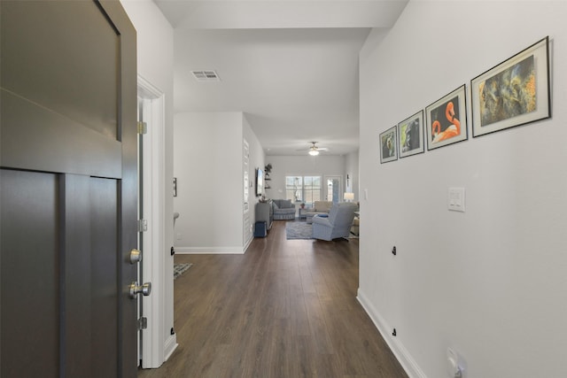 hallway with visible vents, baseboards, and dark wood-style floors