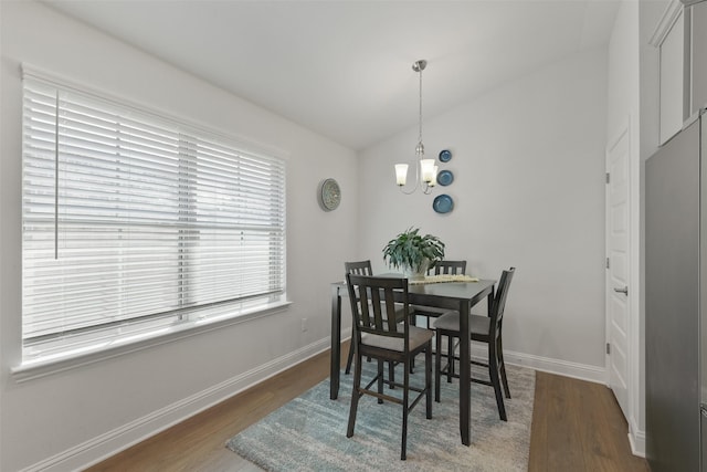 dining area featuring a chandelier, vaulted ceiling, baseboards, and wood finished floors