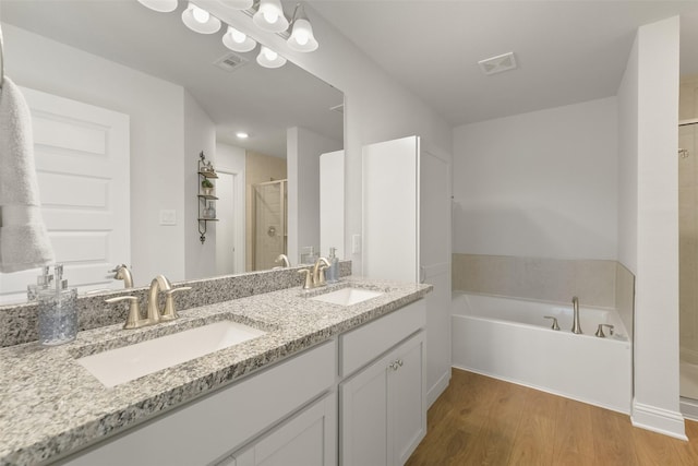 full bathroom with visible vents, a stall shower, wood finished floors, and a sink