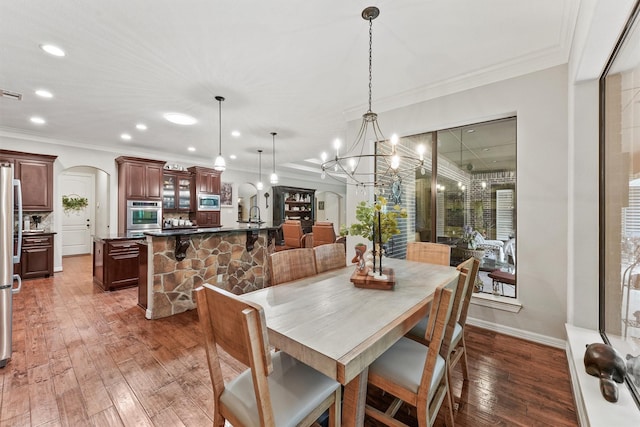 dining space with arched walkways, visible vents, crown molding, and wood-type flooring