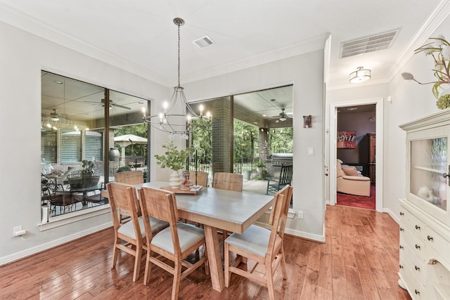 dining space featuring visible vents, light wood-style floors, and ornamental molding