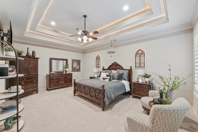 bedroom featuring ceiling fan, a tray ceiling, ornamental molding, and light carpet