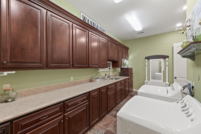 laundry room with washing machine and dryer, cabinet space, visible vents, and a sink