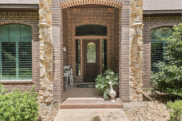 entrance to property with brick siding and roof with shingles