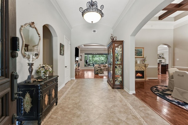 entrance foyer with crown molding, baseboards, and arched walkways