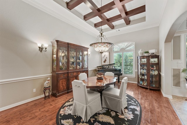 dining room with light wood finished floors, coffered ceiling, baseboards, and arched walkways