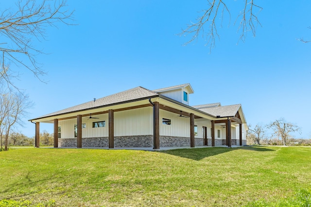 view of side of property with brick siding, a lawn, and ceiling fan